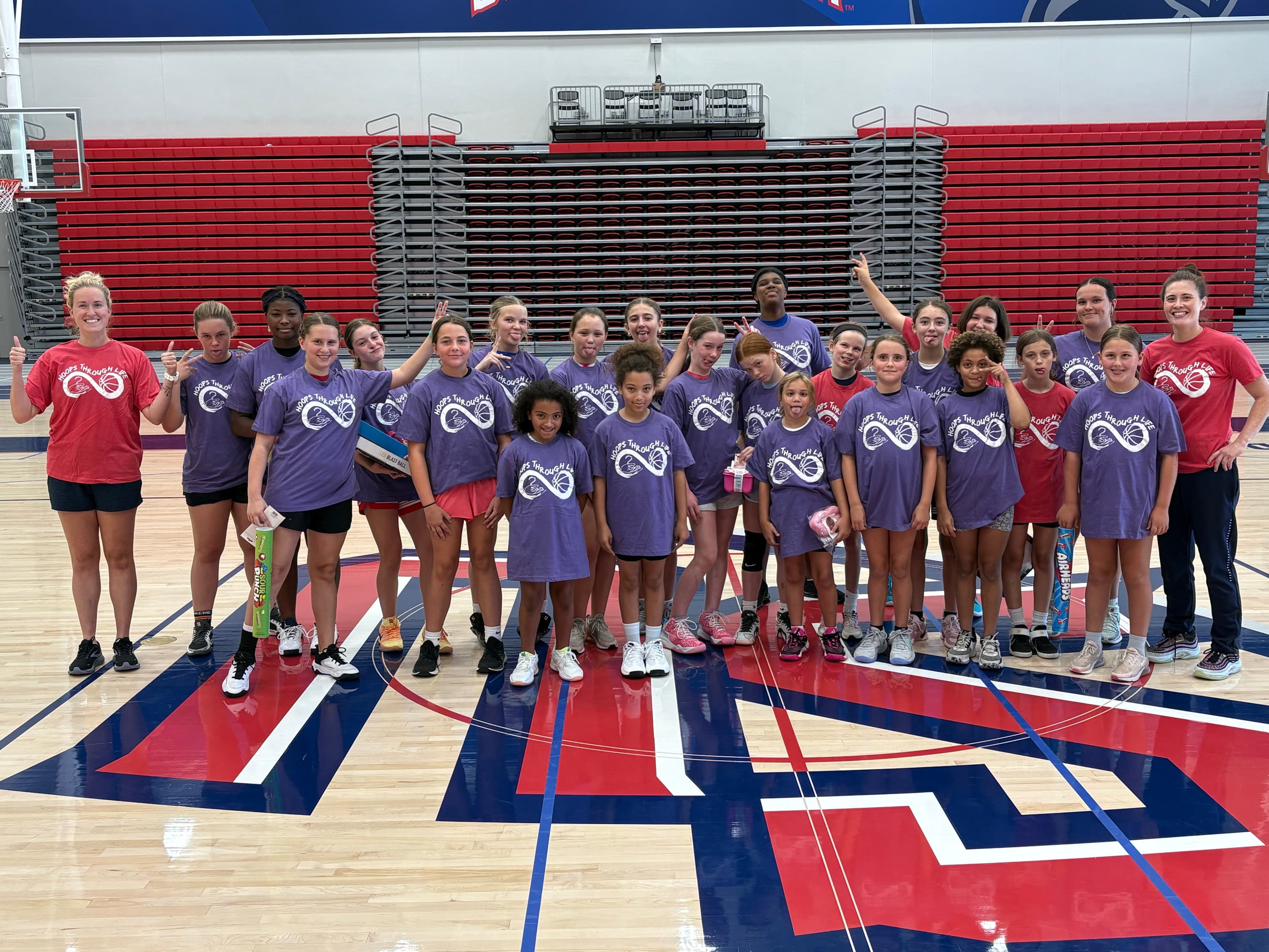 Hoops Through Life campers and coaches gathered together on the court in their purple Hoops Through Life shirts.